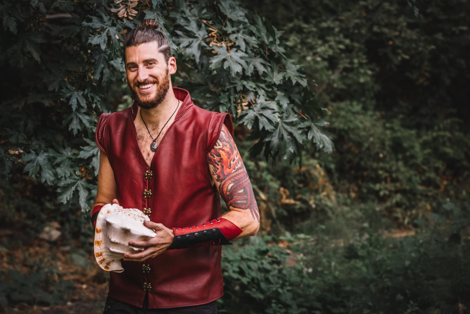 Adam FaeTerra holding a conch shell in a forest setting